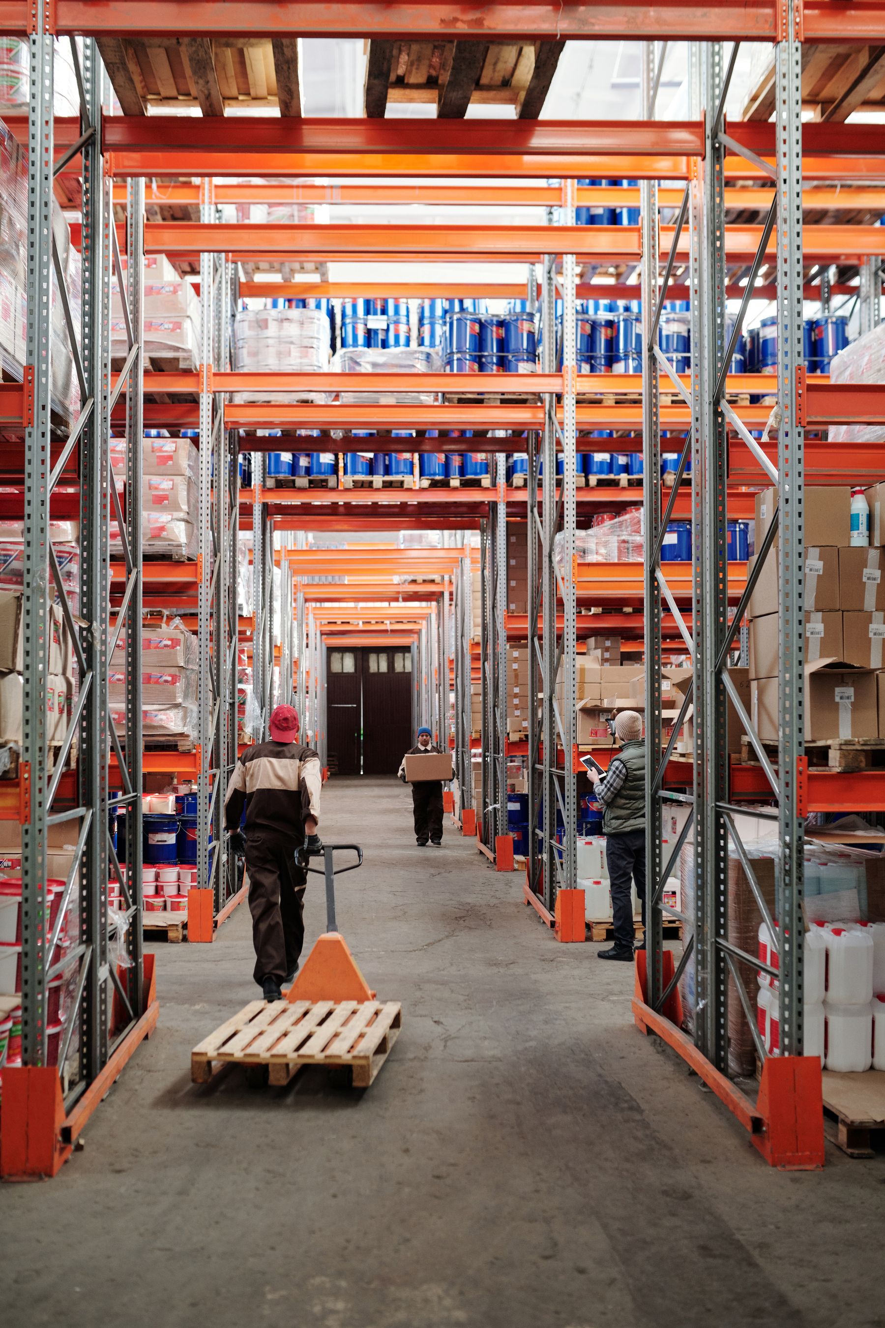Warehouse worker moving a wooden pallet with a hand pallet jack