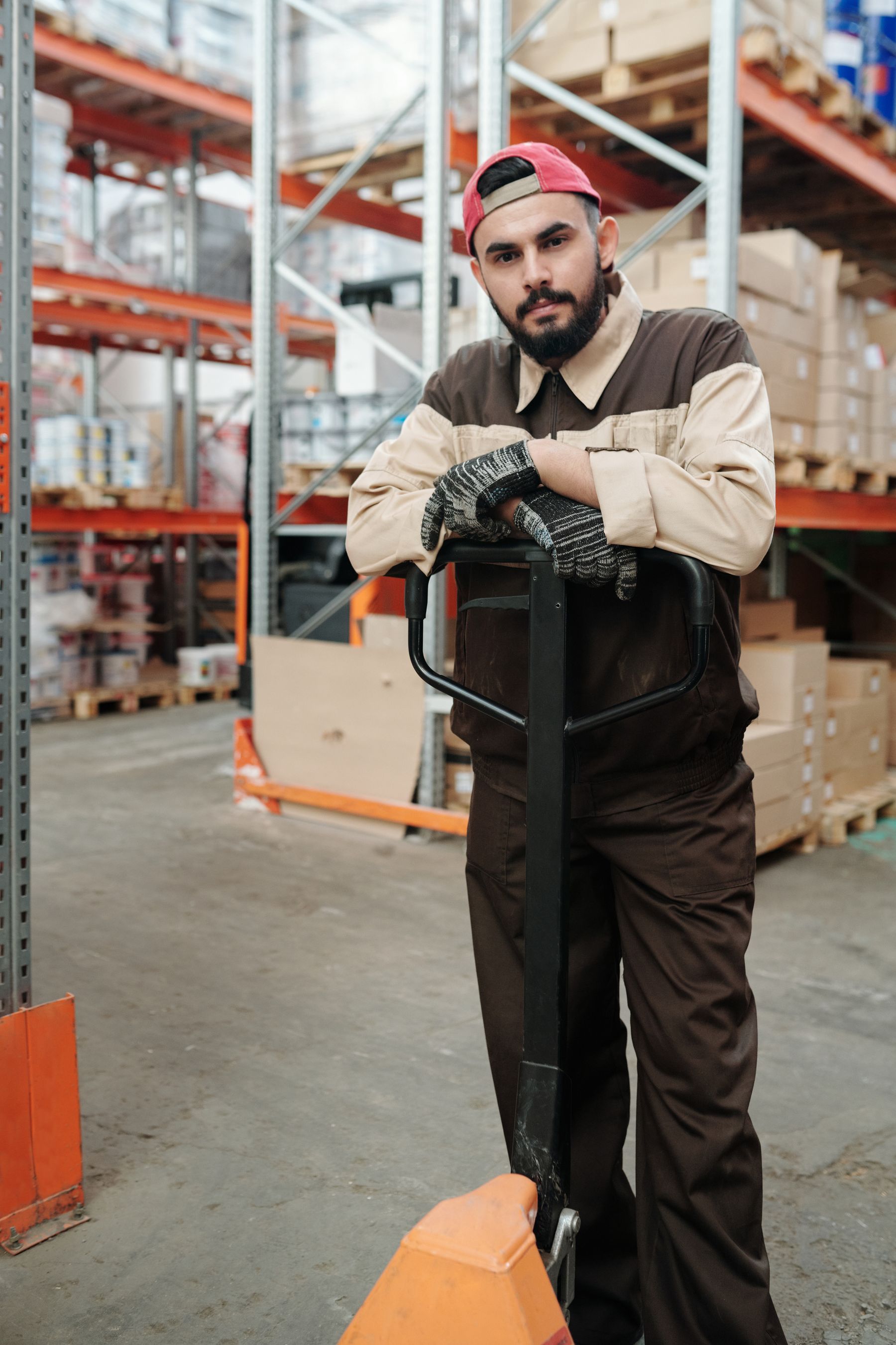 Warehouse employee with a pallet jack beside storage racks